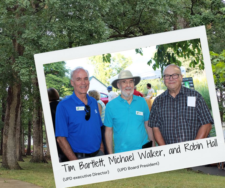 Polaroid of three men (Tim Bartlett, Michael Walker, and Robin Hall) overlaid on a background of trees.